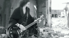 a black and white photo of a man playing a guitar