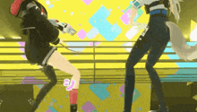 two anime girls are dancing on a stage with a yellow background .