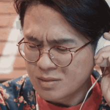 a man wearing glasses and headphones is making a sad face