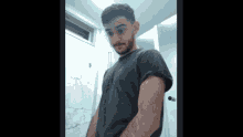a man in a black shirt stands in a bathroom