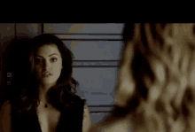 a woman is standing in front of a mirror looking at herself .