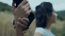 a man is holding a woman 's hand in a field with mountains in the background