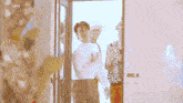 a man in a white shirt is standing in a doorway with two other men .