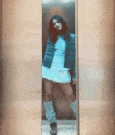 a woman standing in an elevator wearing a blue jacket and white skirt