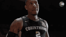 a basketball player wearing a corinthians jersey stands on a court