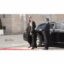 a man in a traditional arabic dress is getting out of a car on a red carpet .