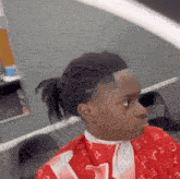 a young boy is getting his hair cut by a barber in a louis vuitton cape .