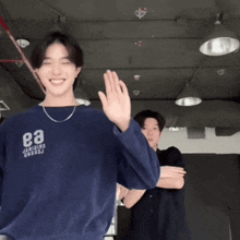 a man wearing a blue shirt with the letter e on it is dancing with another man in a room .
