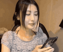 a woman in a lace top holds a cell phone in her hand