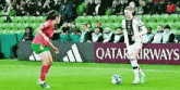 two female soccer players on a field with a qatar airways sign in the background