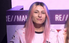 a woman with pink hair stands in front of a sign that says re