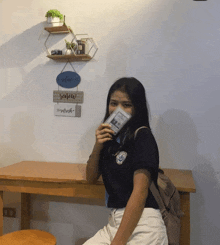 a woman sitting at a table with a sign on the wall that says relax
