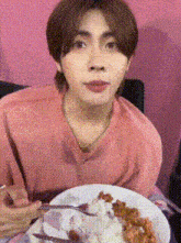 a young man is eating a plate of food with a fork and knife .