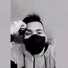 a man wearing a black face mask looks at the camera
