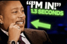 a man in a suit and tie is sitting in front of a neon sign that says i 'm in 1.3 seconds