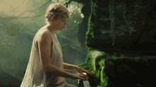 a woman in a white dress plays a piano in a forest