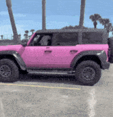 a pink jeep with black trim is parked in a parking lot