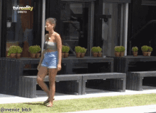 a woman in shorts stands in front of a tv reality logo