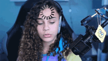 a girl sitting in front of a microphone with a spongebob keychain hanging from it
