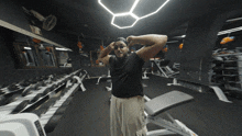 a man stands in a gym with a row of dumbbells