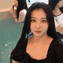 a woman in a black dress is sitting in a swimming pool with other women .
