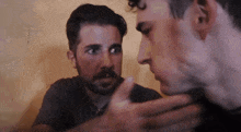 a man with a beard looks at another man
