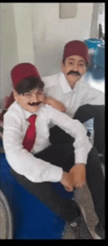 two young boys wearing fake mustaches and hats are sitting next to each other