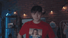 a young boy wearing a red shirt with a picture of a woman on it