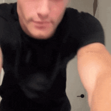 a man in a black t-shirt is taking a selfie in a bathroom .