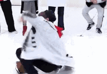 a group of people are dancing on a ice rink while a man is kneeling on the ice .