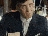 a man wearing a suit and striped shirt is looking at the camera .