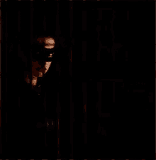 a man wearing a cat mask is peeking out from behind a fence .