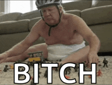 a shirtless man in a diaper is playing with toys and the word bitch is visible