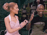 two women are sitting next to each other and one has a shaved head
