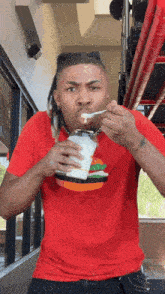 a man in a red shirt with a hamburger on it is eating ice cream with a spoon