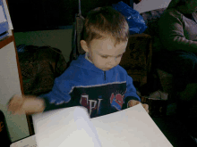 a young boy wearing a blue jacket with the letter p on it is reading a book