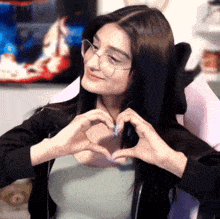 a woman wearing glasses is making a heart with her hands