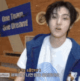 a young man standing in front of a one team one dream sign