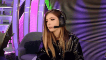 a woman wearing headphones and a microphone is sitting in front of a purple wall