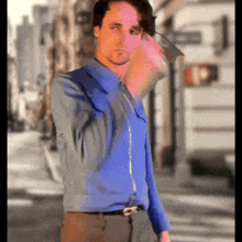 a man in a blue shirt and brown pants is standing on a street