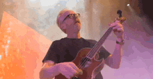 a man with glasses is playing a guitar