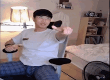a man is sitting in a chair in a bedroom giving a thumbs up sign .