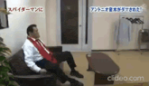 a man in a suit and tie is sitting on a couch in a living room with a coffee table .