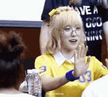 a girl wearing glasses and a yellow shirt with the number 3 on it is giving a high five .