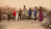 a group of people are standing next to each other on the beach .