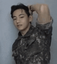 a young man in a military uniform is standing with his arms over his head .
