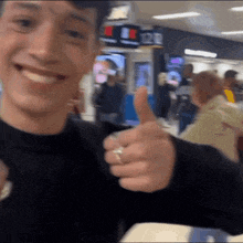 a man with a ring on his finger gives a thumbs up sign