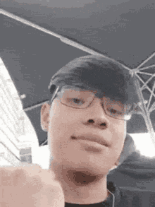 a young man wearing glasses and a hat is making a fist .