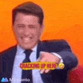 a man in a suit and tie is smiling and pointing with the words cracking up here behind him