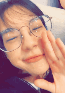 a woman wearing glasses is making a funny face with her eyes closed